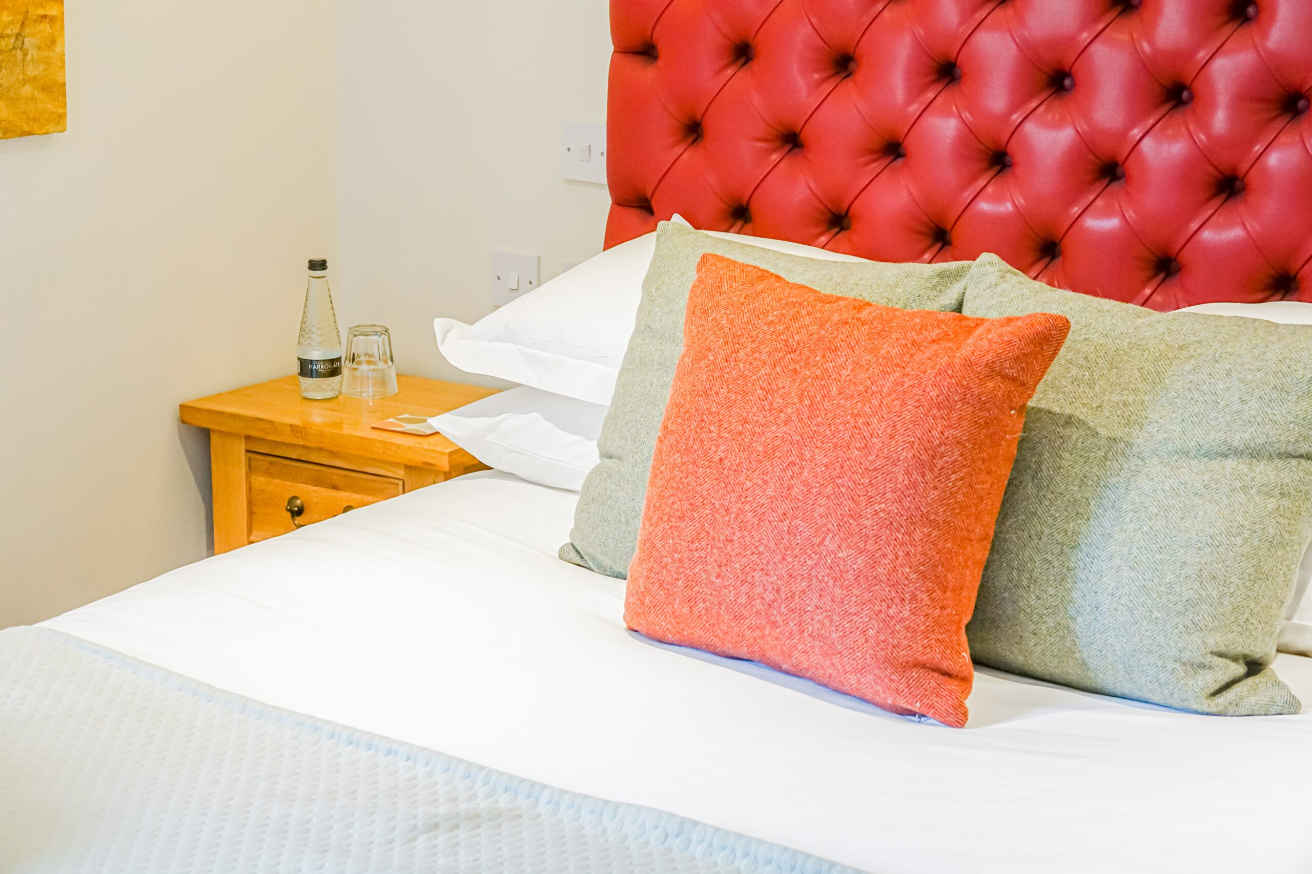 Corner of bed dressed with linen and 3 decorative cushions